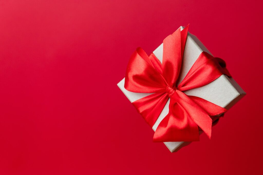 Caja de regalo con lazo rojo sobre fondo rojo
